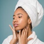 Young woman in a spa setting applying skincare with a fresh clean look.